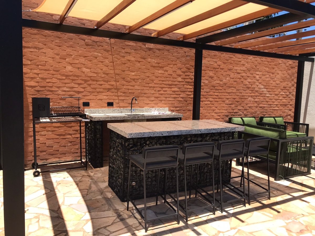 Área gourmet com pergolado metálico, churrasqueira e bancada com estrutura em aço feitos pela Genesis Steel